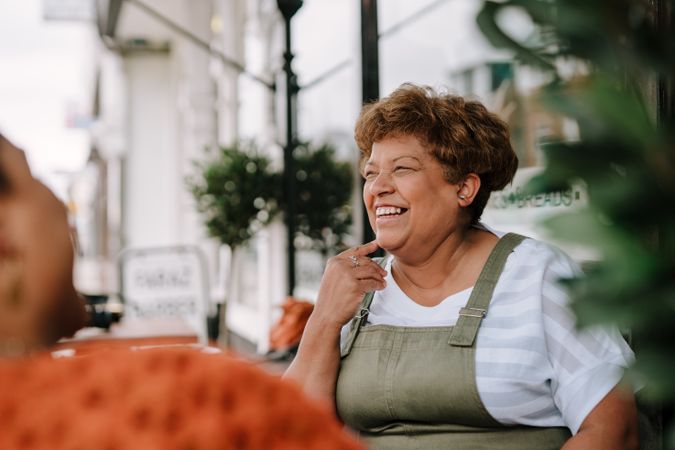 Older Black woman laughing at outdoor table
