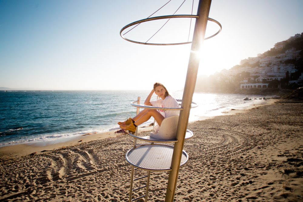 Beautiful blonde model sits on life guard tower on beach