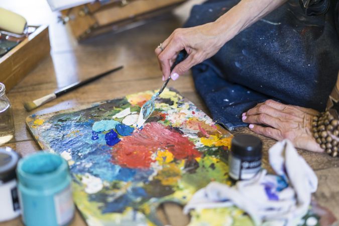 Close up of a woman making colors on a pallete.