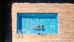 Unrecognizable brunette enjoying sunlight in outdoor swimming po