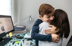 Mother and son hugging while she telecommutes