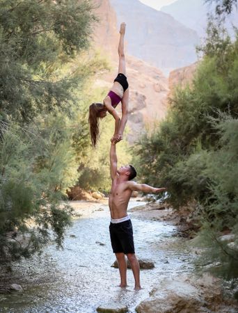 Man holding woman doing split in the air in river