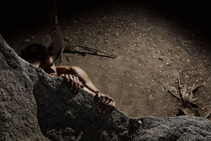 Man practicing rock climbing among large rocks in a forest