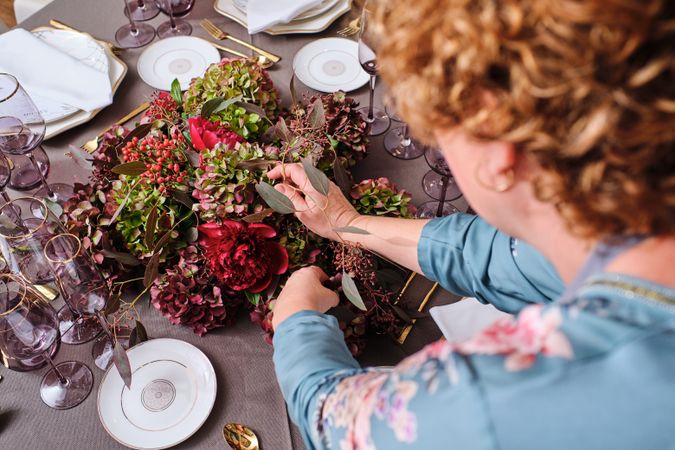 Anonymous woman decorating banquet table with flowers