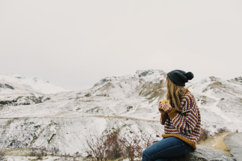 Young woman with cup between mountains