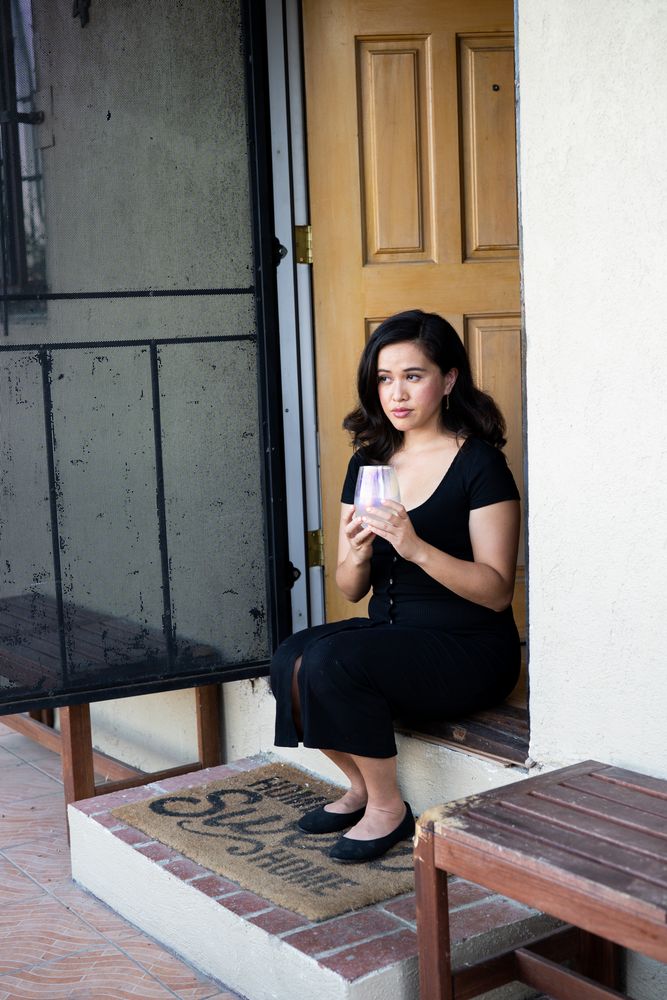 Beautiful woman sitting in front of her house drinking wine and looking out