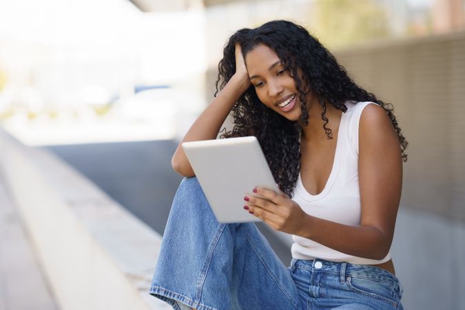 A Joyful and Beautiful Young Woman is Engaged with Her Tablet While Outdoors in Nature