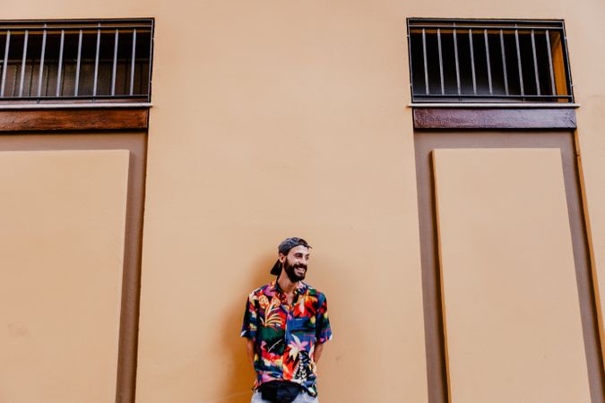 Laughing colorful male against orange wall