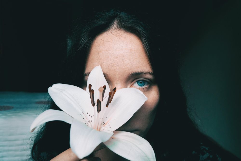 Portrait of woman with blue eyes holding lily flower