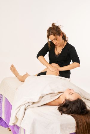 female physiotherapist massaging patient's knee
