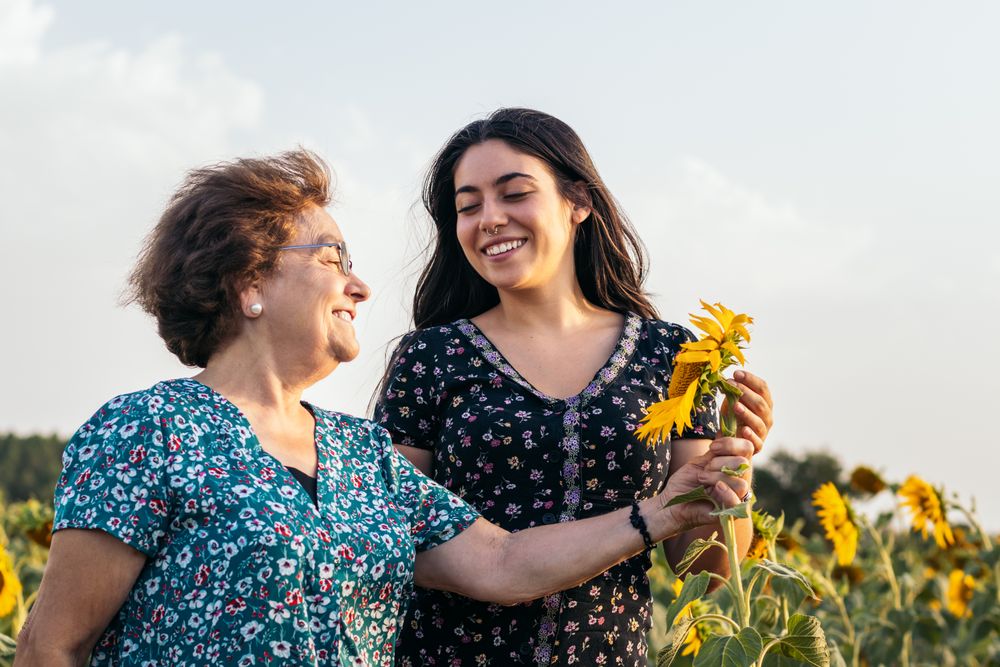 Taking advantage of life Grandmother and granddaughter in a field of sunflowers.