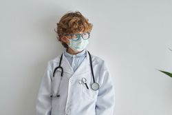 Dreamy boy in medical robe and sterile mask