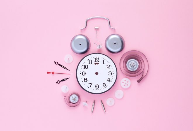 Top view of clock components organized in a circle over pink background