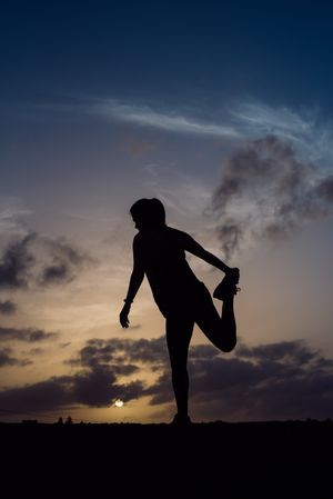 Stretching woman and sky with clouds at sunset