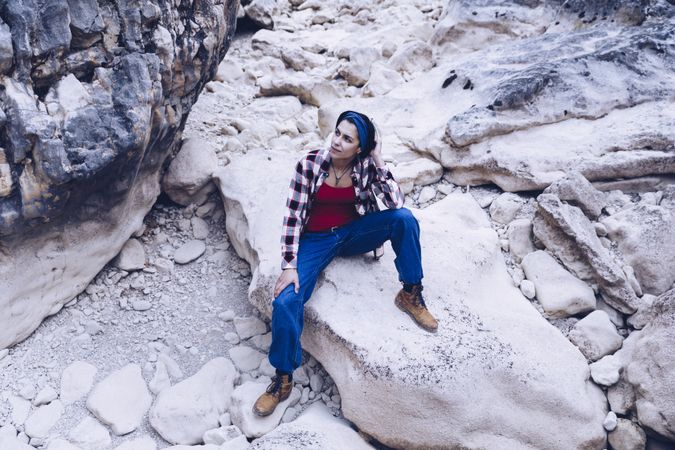 Positive woman sitting on stone