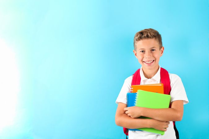 Boy with copybooks and backpack against color background, space for text