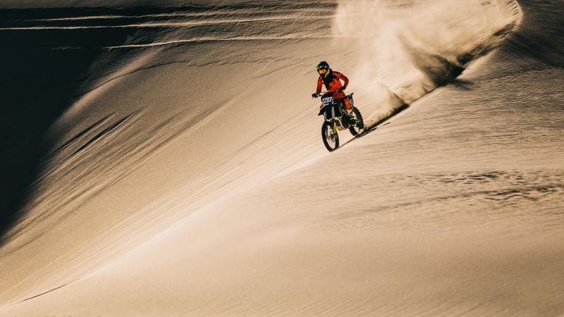 Motocross rider riding dirt bike in desert