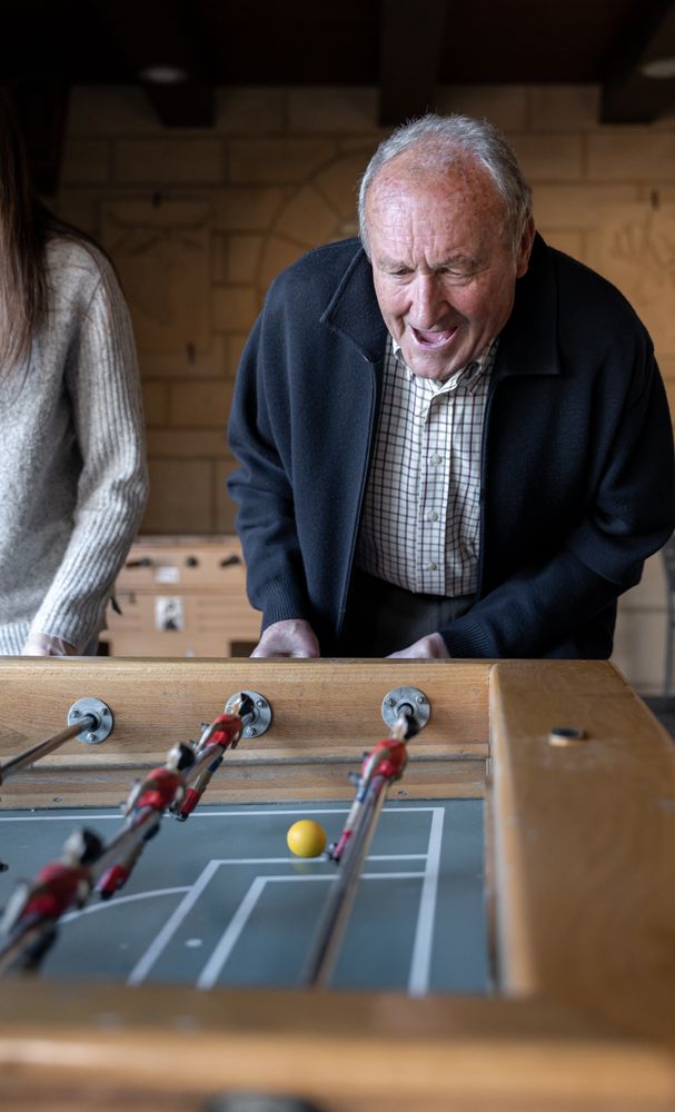 A granddaugther and his grandfather are playing table football game and having fun together