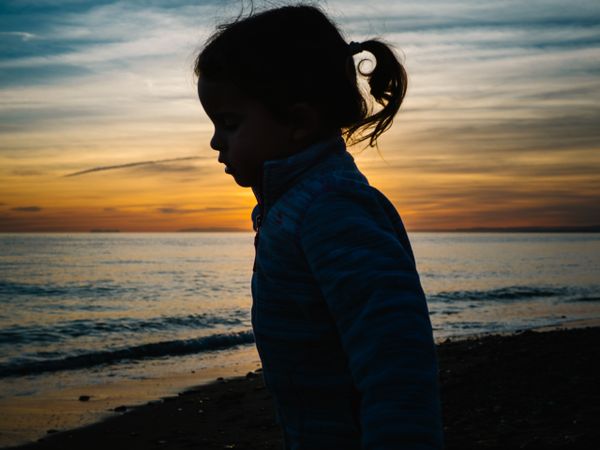 little girl silhouette at beach sunset