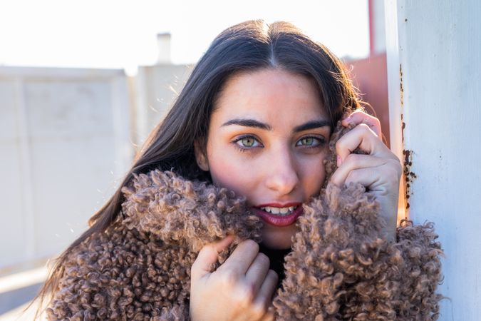 Cheerful woman wrapping in coat on street