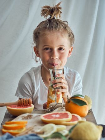 Smiling little boy sitting at table and drinking juice