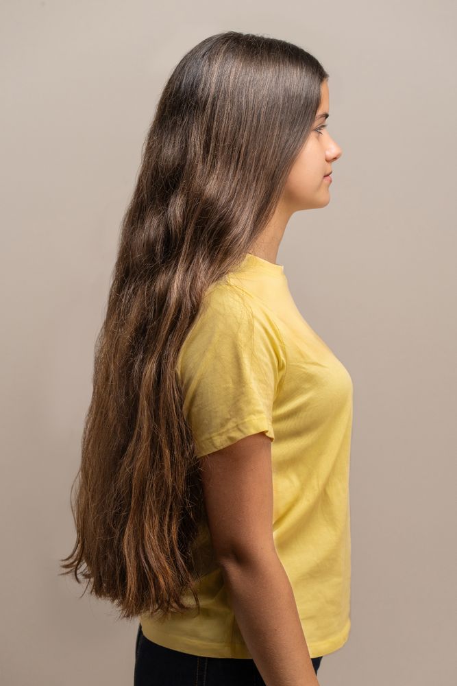 Side view profile of a young woman with very long brown hair.