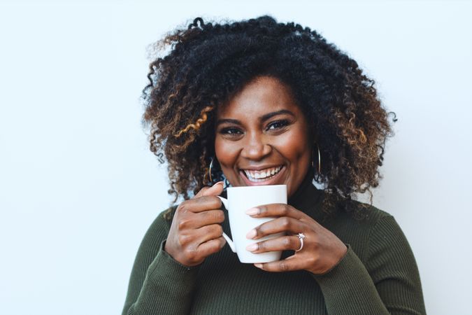 Happy Black woman smiling with cup of coffee in hands