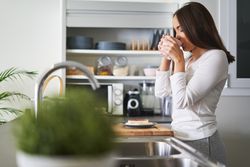 Woman drinking from cup in kitchen