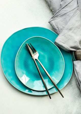 Top view of bright teal plates with silverware