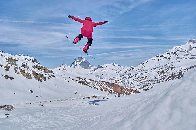 Unrecognizable snowboarder jumping on slope