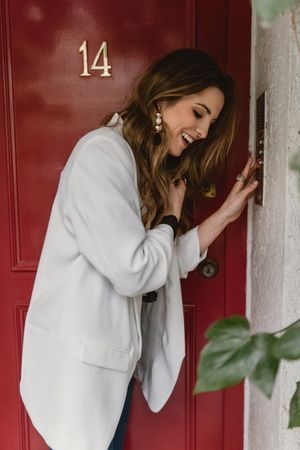 Stylish woman standing near red door