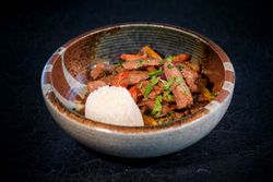 Bowl with delicious fried beef with vegetables and rice on table