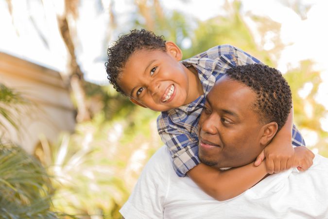 Father and Son Playing Piggyback On Sunny Day