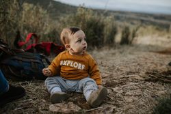 Baby boy sitting outside wearing an “explore” t-shirt
