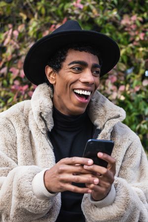 Stylish happy hispanic man with smartphone on street
