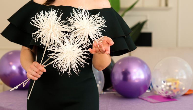 Woman in dress holding white flowers at party