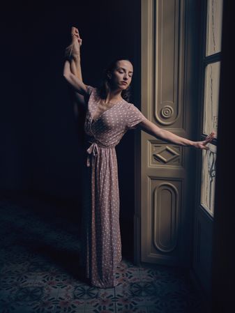 Woman in pointe with raised leg in dim light