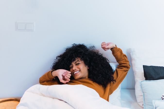 Smiling Black woman waking up in bed