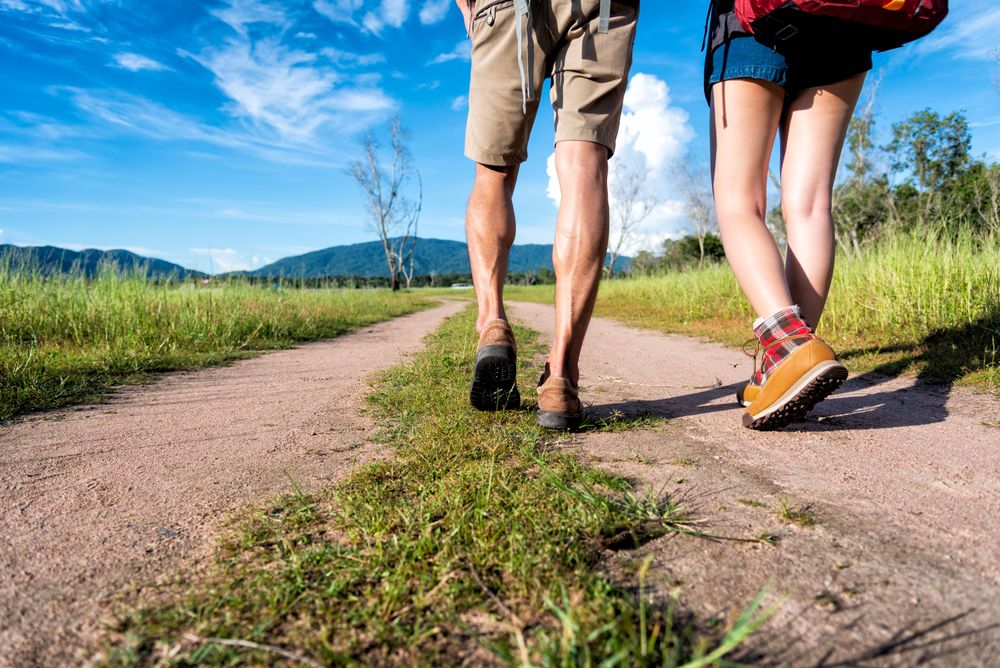 Two people walking on path towards mountain on beautiful day
