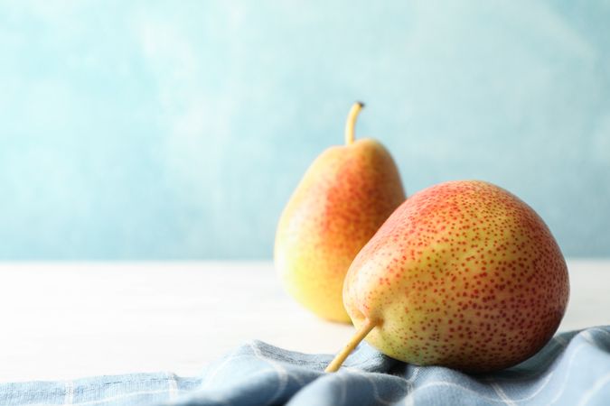 Pears and towel on table against light blue background