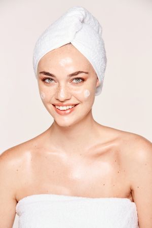 Delighted female with radiant skin applying cream
