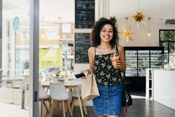 Cheerful hispanic woman leaving restaurant