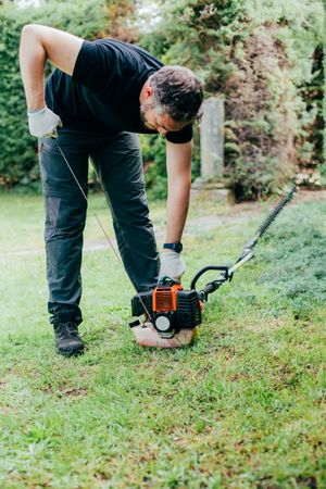 Man switching on a mechanical garden tool