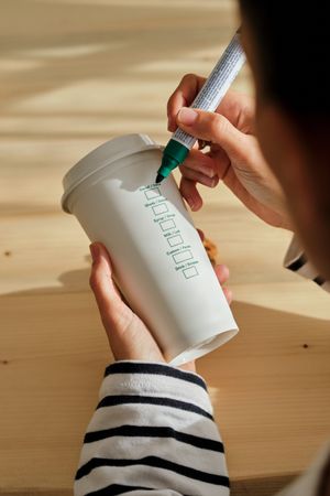 Unrecognizable woman writing at takeaway coffee cup
