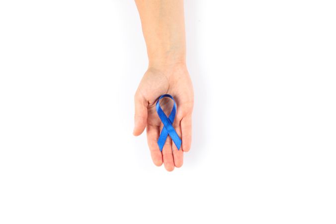 Female hand with blue awareness ribbon isolated on blank background