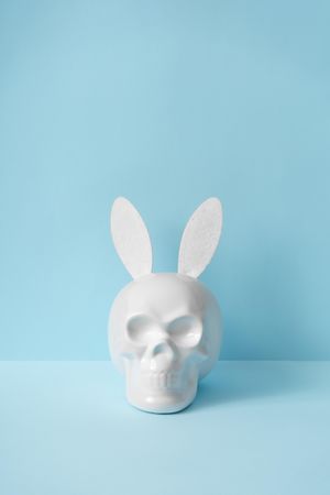 Skull with bunny ears on pastel blue background with copy space
