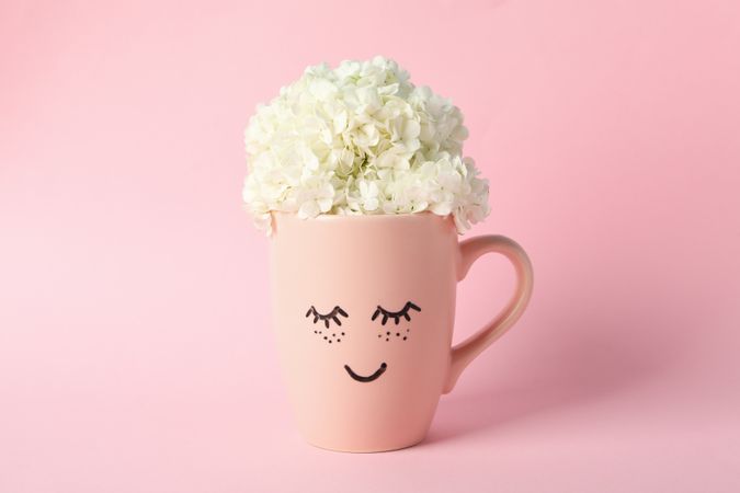 Cup with hydrangea flowers on pink background. Spring plant
