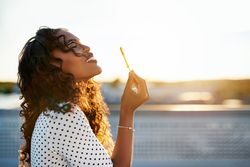 Woman looking up while blowing bubbles on sunny day