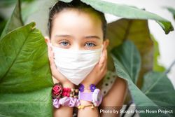 Portrait of a girl in with a face mask  surrounded by green leaves bDAaV0
