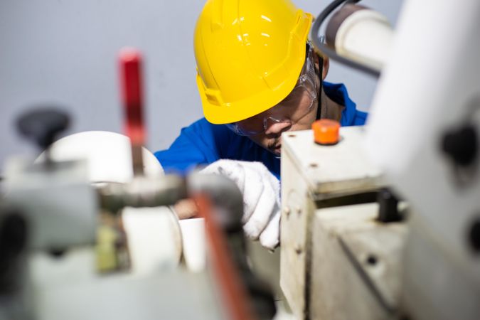 Man in yellow hard hard operating machinery in plant